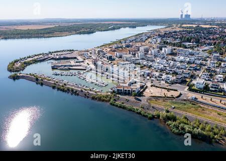 Zwenkau, Deutschland. 19.. Juli 2022. Am Kap Zwenkau am gleichnamigen See (Kraftwerk Lippendorf im Hintergrund) wurden ein Hafen und neue Wohngebäude errichtet. Aus dem ehemaligen Braunkohlebergwerk Zwenkau ist mit einer Fläche von knapp 10 Quadratkilometern der größte See der Region Leipzig hervorgegossen worden. Seit 2011 wird an der Zwenkau-Küste ein komplett neues Quartier errichtet, das Raum für Wohnen und Arbeiten bieten soll. (Luftaufnahme mit Drohne) Quelle: Jan Woitas/dpa/ZB/dpa/Alamy Live News Stockfoto