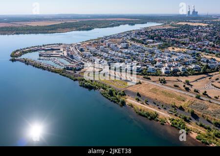 Zwenkau, Deutschland. 19.. Juli 2022. Am Kap Zwenkau am gleichnamigen See (Kraftwerk Lippendorf im Hintergrund) wurden ein Hafen und neue Wohngebäude errichtet. Aus dem ehemaligen Braunkohlebergwerk Zwenkau ist mit einer Fläche von knapp 10 Quadratkilometern der größte See der Region Leipzig hervorgegossen worden. Seit 2011 wird an der Zwenkau-Küste ein komplett neues Quartier errichtet, das Raum für Wohnen und Arbeiten bieten soll. (Luftaufnahme mit Drohne) Quelle: Jan Woitas/dpa/ZB/dpa/Alamy Live News Stockfoto