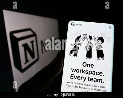 Person, die Mobiltelefon mit der Webseite des US-amerikanischen Softwareunternehmens Notion Labs Inc. Auf dem Bildschirm vor dem Logo hält. Konzentrieren Sie sich auf die Mitte des Telefondisplays. Stockfoto