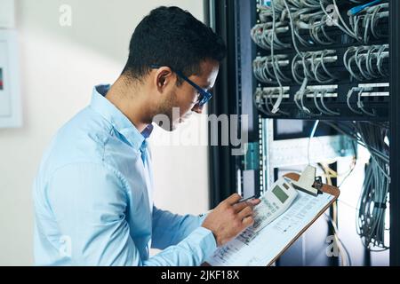 Das summieren sich nicht. Ein hübscher junger Techniker, der alleine steht und auf den Mainframe schaut. Stockfoto