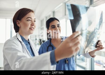 Wir retten ein Leben durch das, was wir geben. Zwei junge Ärzte überprüfen Exrays in einem Krankenhaus. Stockfoto