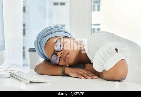 Shes hatte einen langen Tag. Eine attraktive junge Geschäftsfrau schlief auf ihrem Schreibtisch im Büro. Stockfoto