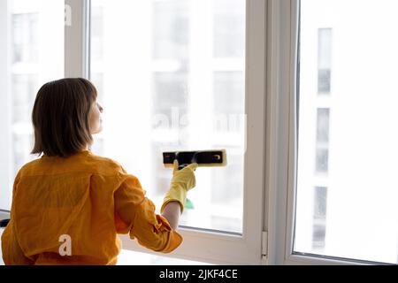 Frau wäscht Fenster in der Wohnung Stockfoto