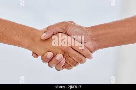 Es ist toll, Sie zu treffen. Zwei unkenntliche Menschen schütteln die Hände vor einem weißen Hintergrund. Stockfoto