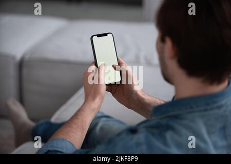Menschen- Und Technologiekonzept. Über Die Schulter Blick Auf Nicht Erkennbaren Mann Mit Smartphone Mit Weißem Leeren Bildschirm Für Mockup, Sitzen Zu Hause, Mak Stockfoto