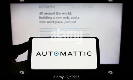 Person, die das Smartphone mit dem Logo des US-amerikanischen Distributed Company Automattic Inc. Auf dem Bildschirm vor der Website hält. Konzentrieren Sie sich auf die Telefonanzeige. Stockfoto