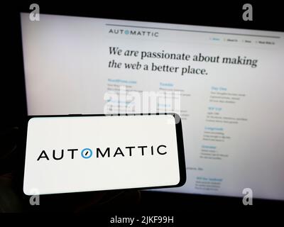 Person, die Mobiltelefon mit dem Logo des amerikanischen Distributed Company Automattic Inc. Auf dem Bildschirm vor der Webseite hält. Konzentrieren Sie sich auf die Telefonanzeige. Stockfoto