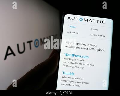 Person, die Mobiltelefon mit der Website des US-Distributed Company Automattic Inc. Auf dem Bildschirm vor dem Logo hält. Konzentrieren Sie sich auf die Mitte des Telefondisplays. Stockfoto