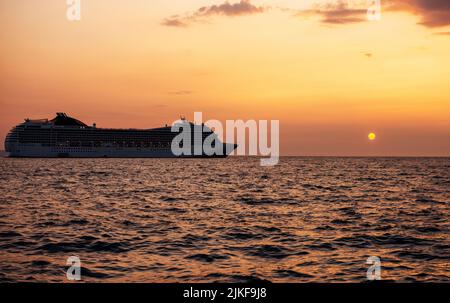 Kreuzfahrt-Linienschiff auf offener See. Passagierfähre, die bei heißem Sonnenuntergang segelt. Stockfoto