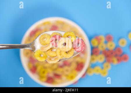 Getreideringe mit Milch, Nahaufnahme im Löffel, Draufsicht, blauer Hintergrund Stockfoto
