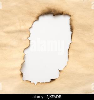 Gealtertes, faltiges beiges Papier mit verbranntem Loch im Grunge-Design Stockfoto