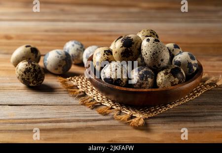 Wachteleier in einer Holzschüssel vor einem hölzernen Hintergrund. Stockfoto