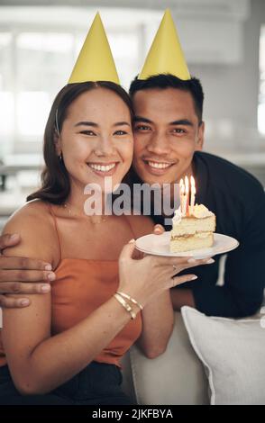 Dankbar für jedes Jahr des Lebens. Ein junges Paar posiert mit einem Stück Kuchen zu Hause. Stockfoto