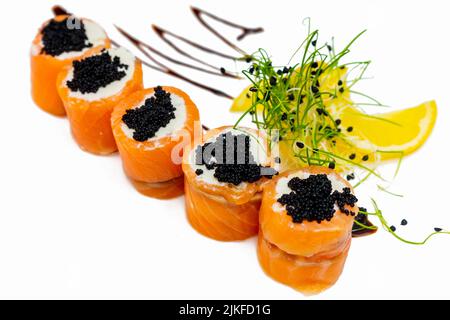 Sushi-Brötchen von rotem Fisch mit schwarzem Kaviar auf einem weißen Teller Stockfoto