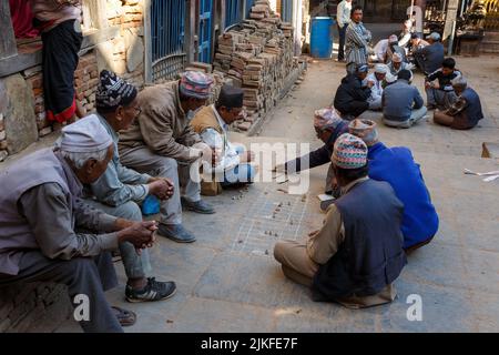 Bhaktapur, Nepal - 15. November 2016: Nepalesische Männer spielen traditionelles Spiel auf der Straße. Spielen mit Bambusstäben und Kieselsteinen. Stockfoto