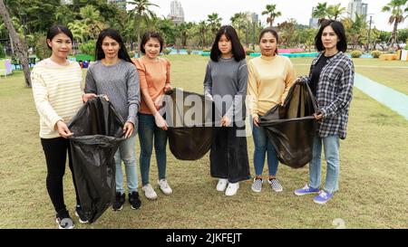 Asia Woman Group Team Volunteer Pick up Trash Plastics Müll Plastikmüll. Freund, der Plastikmüll im Park Concept Team Vo in die Tüte legt Stockfoto