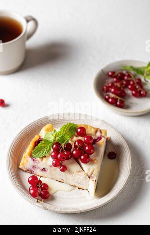 Hüttenkäse-Auflauf mit frischen Sommerbeeren auf weißem Tisch für ein gesundes Frühstück. Vertikale Ausrichtung Stockfoto