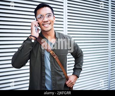 Immer ein Lächeln auf meinem Gesicht. Ein junger Mann, der in der Stadt telefoniert. Stockfoto
