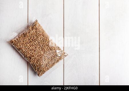 Hanfsamen in transparenter Verpackung auf hellem Holzhintergrund, Mockup. Stockfoto