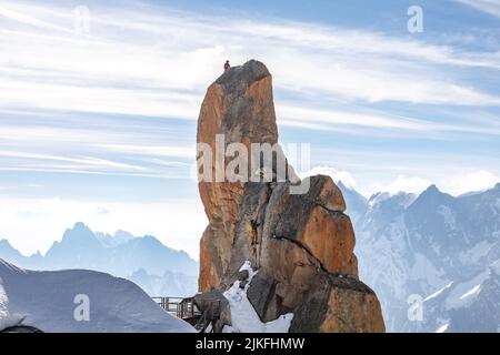 Kletterer klettern auf einem großen Felsen auf dem Gipfel der Aiguille du Midi im Mont Blanc, Frankreich Stockfoto