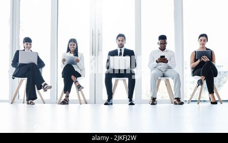 Zusammenkommen für alle Geschäfte. Eine Gruppe von Geschäftsleuten, die digitale Geräte in einem Büro nutzen. Stockfoto