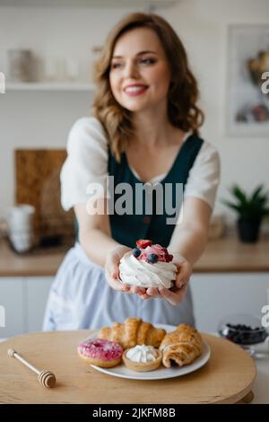 Hausfrau hält einen Kuchen in den Händen, während sie in der Küche steht Stockfoto