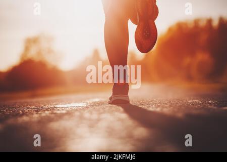Frau, die am Abend bei Sonnenuntergang im Freien läuft Stockfoto