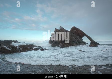 Landschaft von natürlichen Meeresbogen und Meereswellen. Berühmte Felsformation an der Moray Coast, Schottische Highlands, Schottland. Bow Fiddle Rock. Stockfoto