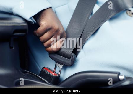 Nahaufnahme einer nicht erkennbaren schwarzen Frau, die Sicherheitsgurt im Auto fastet, Platz kopieren Stockfoto