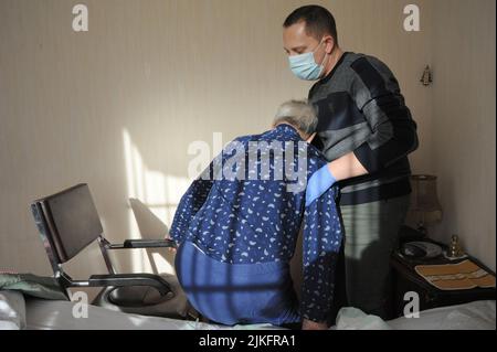 Die liberale Krankenschwester führt eine komplette Toilette im Haus eines Patienten aus, der aus dem Bett kommt. Stockfoto