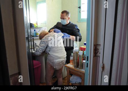 Eine private Krankenschwester führt eine komplette Toilette im Haus eines älteren Patienten durch. Stockfoto