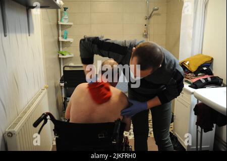 Eine private Krankenschwester führt im Haus eines 69-jährigen Patienten eine komplette Toilette durch. Stockfoto