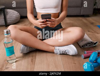 Nahaufnahme einer jungen Frau auf dem Handy nach dem Training Stockfoto