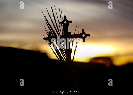 Karwoche. Prozessionskreuz und Zweige in wunderschöner Sonnenuntergangsszenerie. Traditionelle katholische Feier Palmsonntag. Christlicher Glaube. Religiöse Symbole Stockfoto