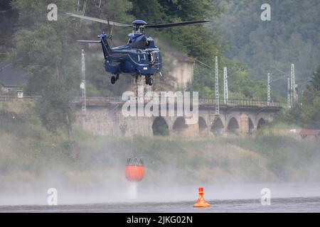 Schmilka, Deutschland. 02. August 2022. Ein Hubschrauber holt mit einem externen Wasserbehälter Wasser aus der Elbe, um einen Waldbrand im Nationalpark Sächsische Schweiz zu löschen. Quelle: Sebastian Kahnert/dpa/Alamy Live News Stockfoto