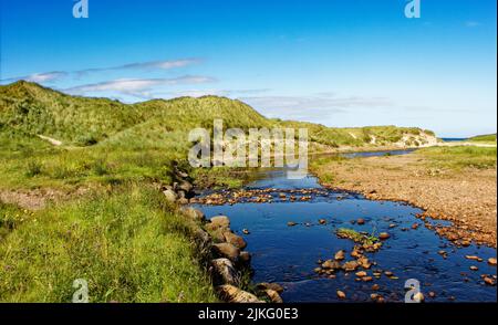 GROSSER SANDSTRAND GAIRLOCH SCHOTTLAND DER FLUSSSAND FLIESST AN DÜNEN IN DER NÄHE DES STRANDES VORBEI Stockfoto