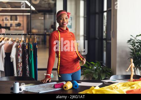 Porträt eines lächelnden afroamerikanischen Modedesigners am Schreibtisch im Studiobüro Stockfoto