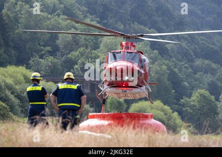 Schmilka, Deutschland. 02. August 2022. Ein Hubschrauber fliegt über ein Feuerwasserbecken, um einen Waldbrand im Nationalpark Sächsische Schweiz zu löschen. Quelle: Sebastian Kahnert/dpa/Alamy Live News Stockfoto