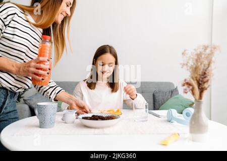 Weiße Mutter und Tochter lächeln beim Frühstück zu Hause Stockfoto