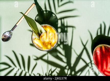 Thailändisches Dessert mit Mango und klebrigem Reis und Kokosmilch, verziert mit Nelke, Zuckerrohrblatt, roher Mango-Rückseite Stockfoto