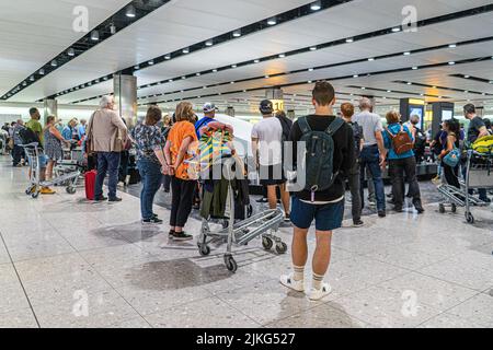 Heathrow , London, Großbritannien 2. August 2022. Passagiere, die ihr Gepäck in der Gepäckhalle am Heathrow Terminal 2 abholen möchten. Der Flughafen Heathrow hat die Anzahl der Passagierabflüge auf 100.000 pro Tag begrenzt, bis mehr Bodenpersonal eingestellt wird, da der Flughafen immer noch mit einem Mangel an Gepäckabfertigungskräften zu kämpfen hat. British Airways sagte, dass sie den Verkauf von Kurzstreckenflügen vom Londoner Flughafen Heathrow für etwa eine Woche aussetzen würde, um die Buchungen zu begrenzen, um die durch die boomende Nachfrage und Personalmangel verursachten Reiseunterbrechungen zu lindern. Credit. amer Ghazzal/A Stockfoto