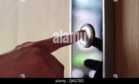 Nahaufnahme mit weiblicher Hand, die die Aufzugstaste im Business Center drückt. Stockfoto