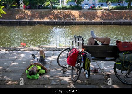 Radler, der sich im Schatten am Fluss Ouse, York, Großbritannien, ausruhen kann. Sommerhitze in York. Eine neue britische Rekordtemperatur von 40,3C wurde tagsüber in Lincolnshire eingestellt. York, 2022, Großbritannien. Stockfoto