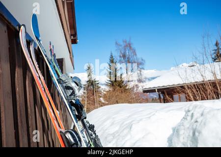 Snowboards und Skier stehen auf dem alpinen Resort in der Nähe des Gebäudes Stockfoto