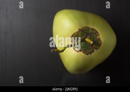 Nahaufnahme von junger grüner Kokosnuss auf schwarzer Tischplatte, gesunde tropische Früchte, die nicht vollständig gereift sind, Draufsicht, Platz für Text Stockfoto