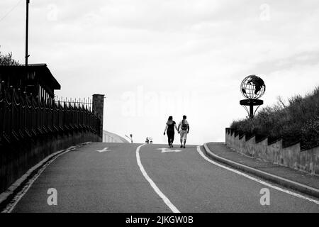 Eine Graustufenaufnahme eines jungen Paares, das die Straße entlang läuft. Gyumri, Armenien. Stockfoto