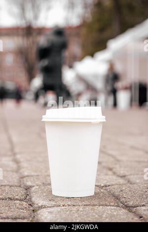 Die Öko-Papier-Kaffeetasse auf dem Asphalt mit leerem Copyspace, vertikal Stockfoto