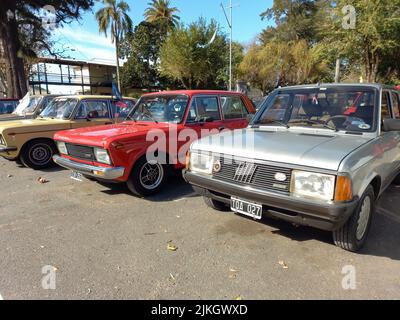 Alte rote Fiat 128 Europa 1978 - 1982 und graue Super Europa 10983 - 1985 viertürige Limousine im Park. Sonniger Tag. Natur, Bäume. Oldtimer-Show. Copyspace Stockfoto