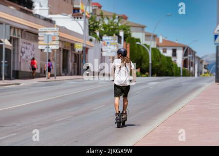 ronda, malaga, spanien 20. juni 2022 junger Mann mit Dreadlocks auf einem Elektro-Skateboard, der auf der Autobahn unterwegs ist Stockfoto