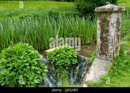 Kleiner Wasserfall durch eine alte Steinsäule Stockfoto